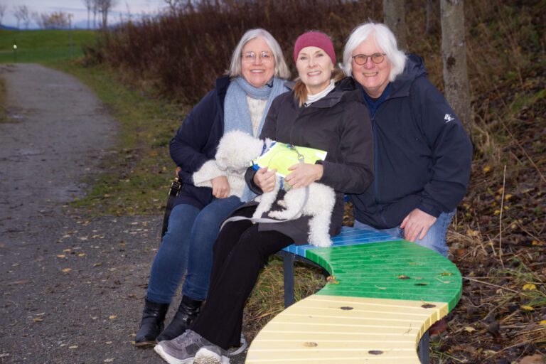 Fra venstre: Elke Seitz, Cecilie Korsan Sundet, Per Henning Dahl og hunden Rocky på Tenkebenken ved Midtsandtangen. Benken ble gitt til parken av Human-Etisk Forbund Malvik lokallag, og ble malt i regnbuefarger etter Pride-skytingen i Oslo i 2022 – som symbol på mangfold, inkludering og respekt. Foto: Human-Etisk Forbund Malvik